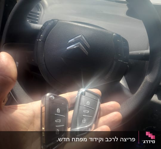 שני מפתחות רכב חכמים ביד מול הגה